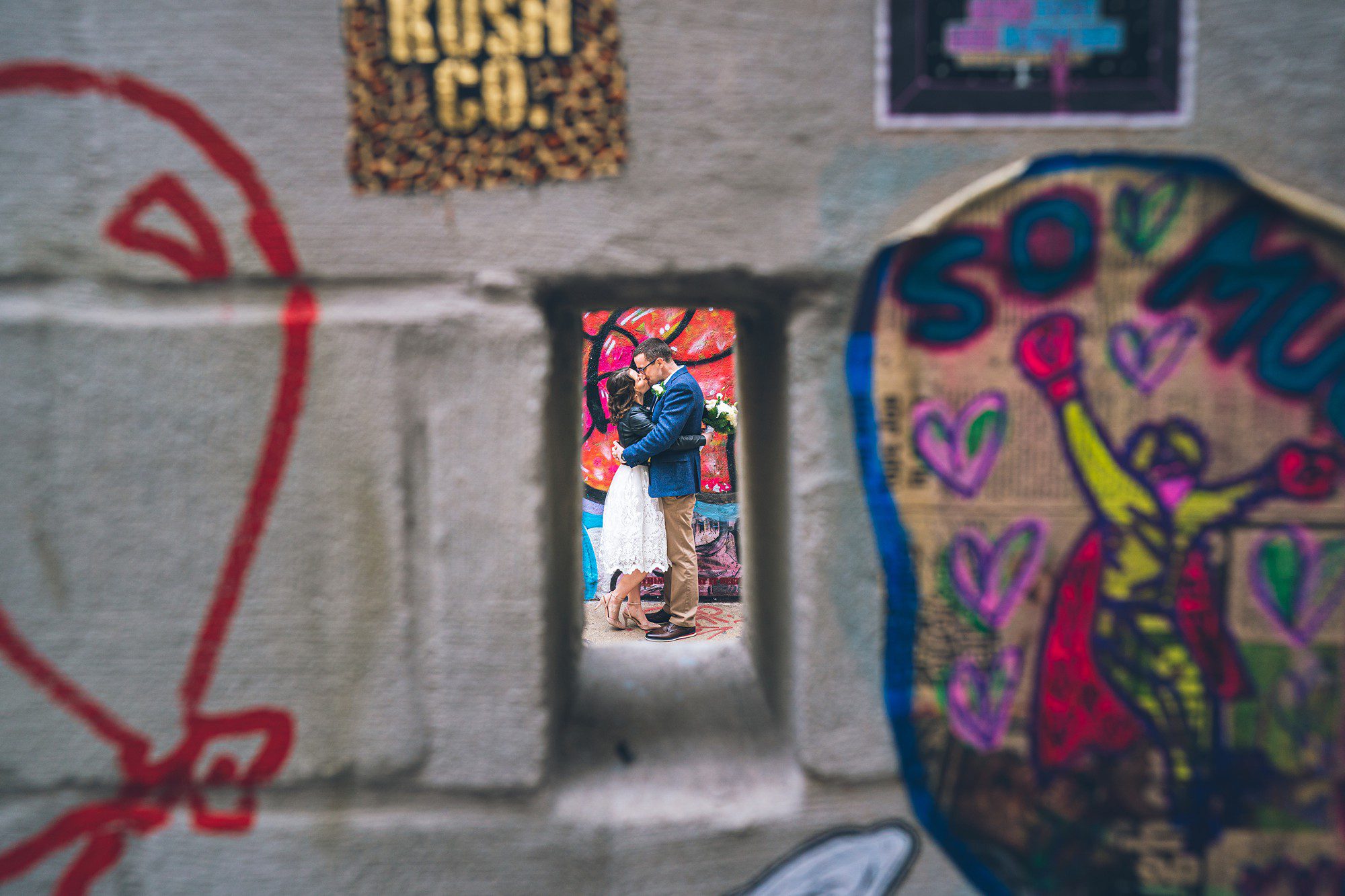 Eloped couple photographed through a graffiti wall by Sascha Reinking Photography, New York Elopement Photographer